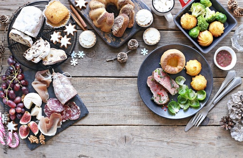 Christmas dinner table with roast beef,yorkshire pudding,appetizers platter and traditional cake. Christmass celebration, festive family dinner. Overhead view.