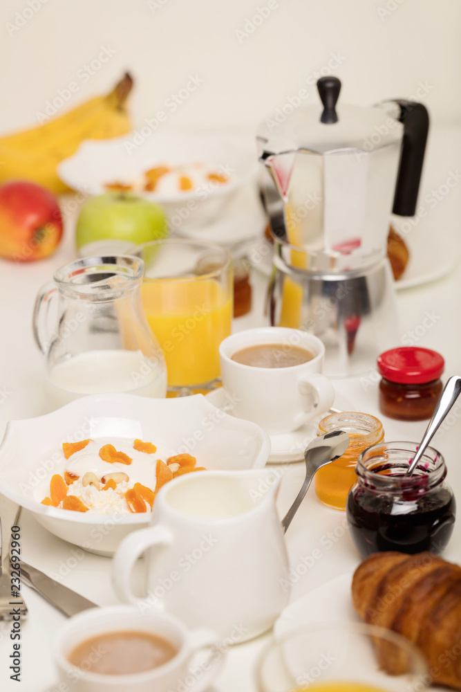 Breakfast time. Croissants and orange juice, jam and honey. Coffee with cream or milk. Fruits - bananas, red and green apples. Ricotta with sour cream, nuts and dried apricots.