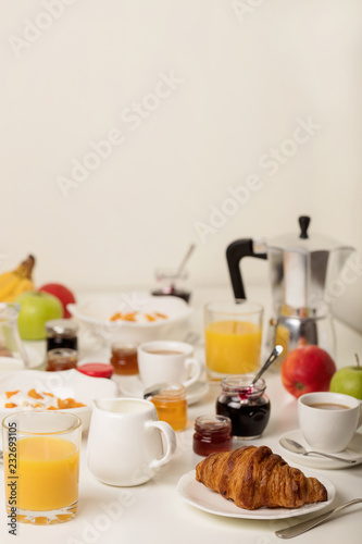Breakfast time. Croissants and orange juice  jam and honey. Coffee with cream or milk. Fruits - bananas  red and green apples. Ricotta with sour cream  nuts and dried apricots.