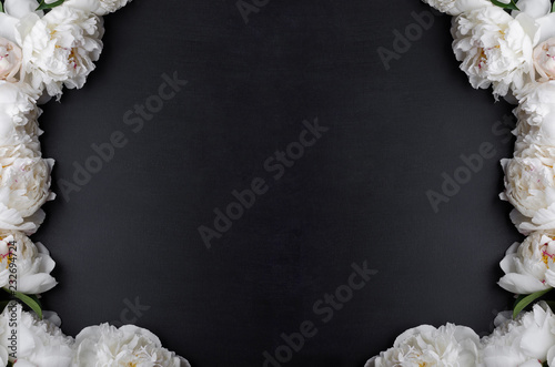 White peonies on black background with empty space surrounded with flowers. Copy space