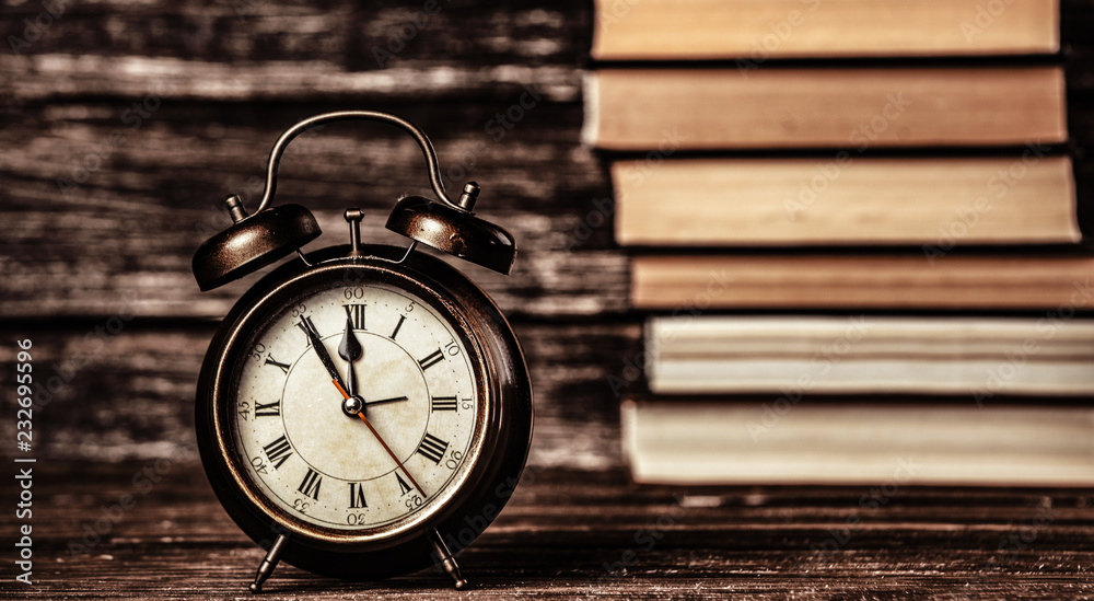 Alarm clock and books on wooden table and background Alarm clock and books on wooden table and background