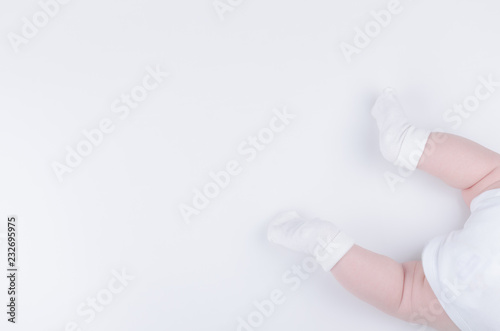 Infant in white clothes lies on stomach