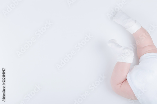 Baby’s legs. Crawling baby in white socks and bodysuit