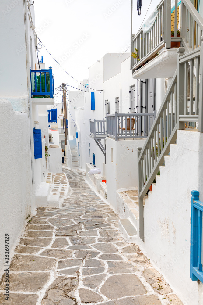 Fototapeta premium Traditional houses with blue doors and windows in the narrow streets of greek village in Mykonos, Greece