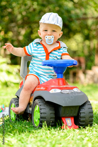 happy smiling child boy sitting on a toy car in park