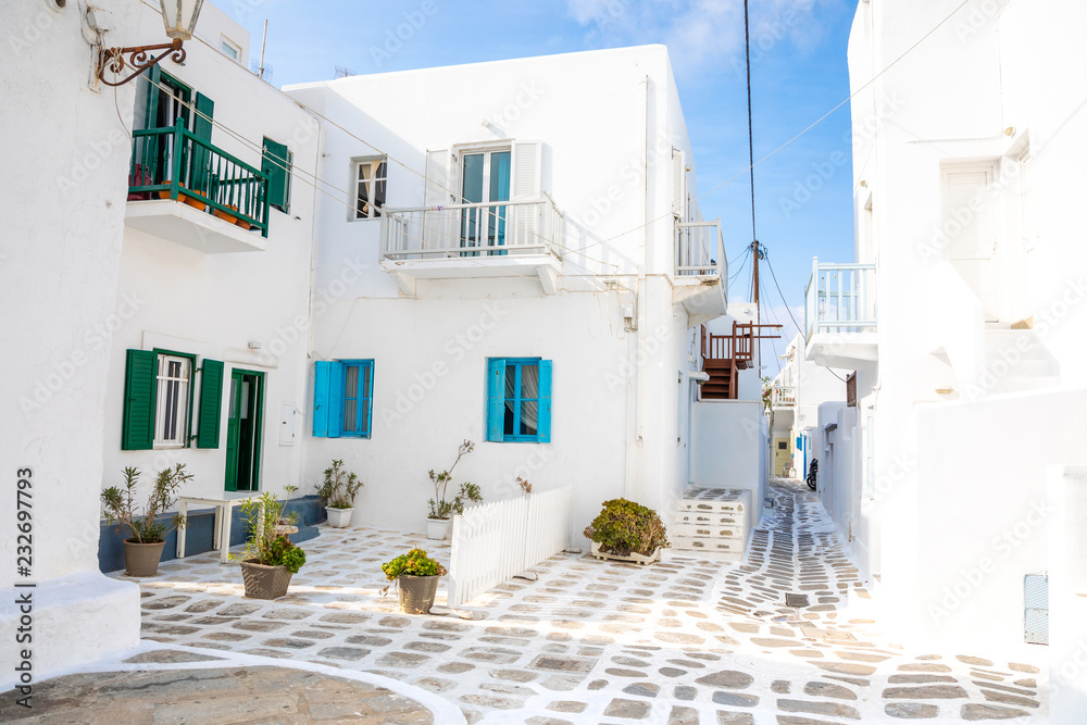 Fototapeta premium Traditional houses with blue doors and windows in the narrow streets of greek village in Mykonos, Greece