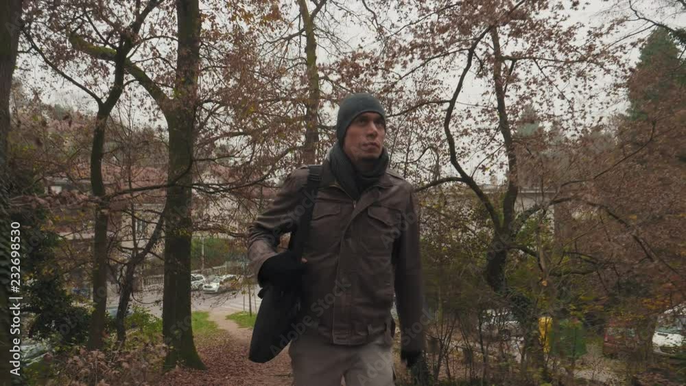 Young man in the forest park in autumn on misty foggy day. Walking up the stairs. Shot from BUSINESS ON THE GO - WORKING WITH TECHNOLOGY IN THE NATURE concept sequence. Other shots also available. Young man in the forest park in autumn on misty foggy day. Walking up the stairs. Shot from BUSINESS ON THE GO - WORKING WITH TECHNOLOGY IN THE NATURE concept sequence. Other shots also available.