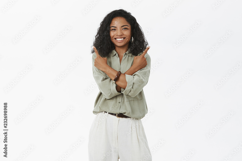 Both choices good, decide. Attractive friendly-looking creative dark-skinned entrepreneur in blouse and pants crossing arms over body pointing different sides and smiling, redommending all products Both choices good, decide. Attractive friendly-looking creative dark-skinned entrepreneur in blouse and pants crossing arms over body pointing different sides and smiling, redommending all products