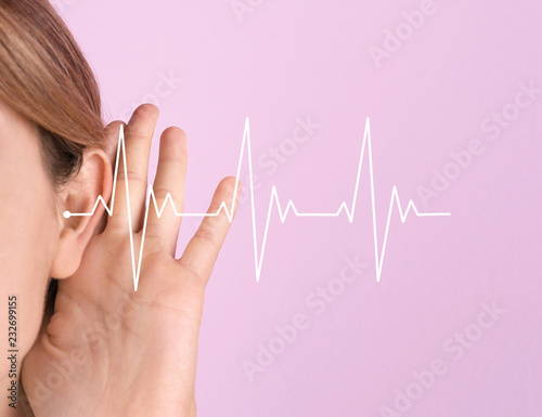 Young woman with hearing problem on color background, closeup. Space for text photo