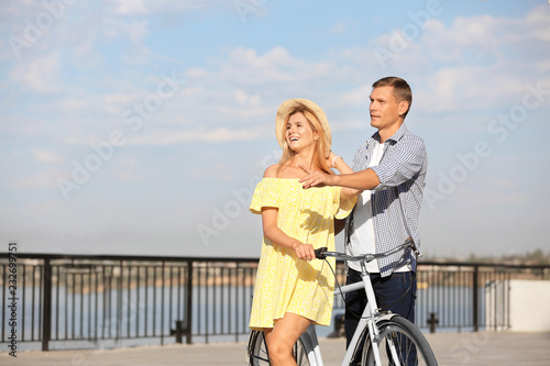 Happy couple with bicycle outdoors on sunny day