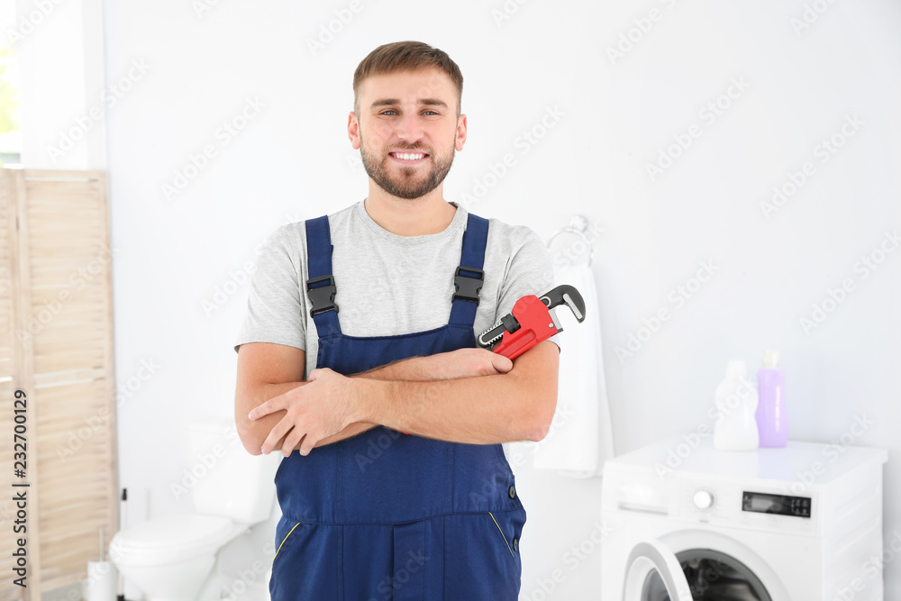 Obraz premium Young plumber with wrench near washing machine in bathroom