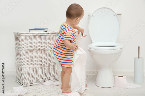 Bild auf Leinwand Cute toddler playing with toilet paper in bathroom