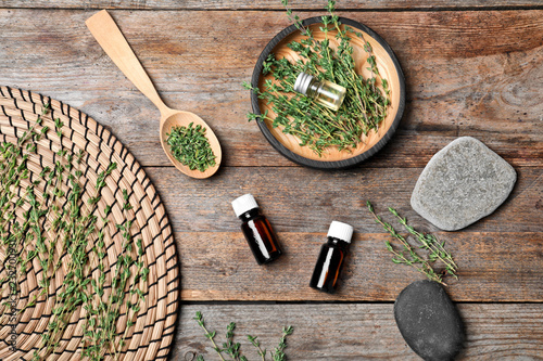 Flat lay composition with natural essential oil and thyme on wooden background