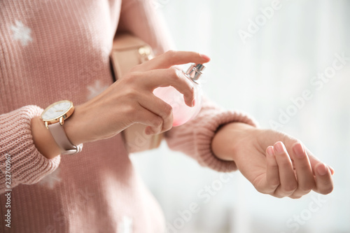 Young woman using perfume indoors, closeup photo