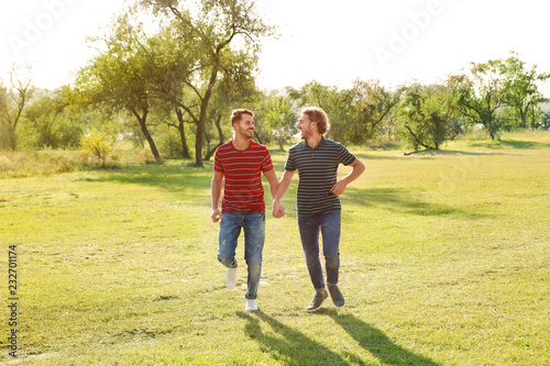 Happy gay couple running in countryside on sunny day © New Africa
