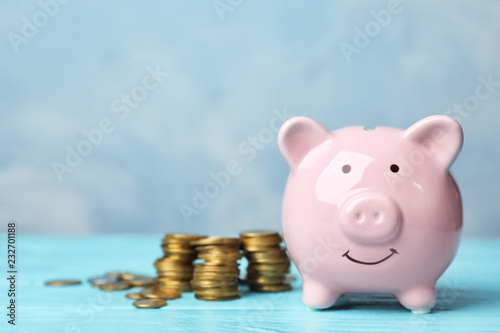 Piggy bank with coins on color table. Space for text
