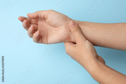 Woman checking pulse on color background, closeup photo