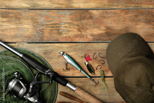 Flat lay composition with fishing equipment and space for text on wooden background