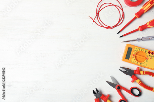 Flat lay composition with electrician's tools and space for text on wooden background