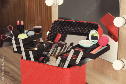 Beautician case with professional makeup products and tools on dressing table