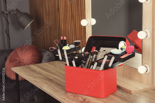 Beautician case with professional makeup products and tools on dressing table