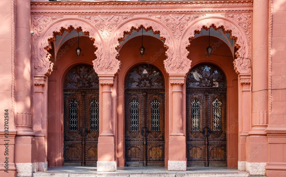Three arched wooden doors in a row on the red facade of Synagogue of Uzhgorod, Ukraine