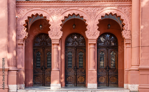 Three arched wooden doors in a row on the red facade of Synagogue of Uzhgorod, Ukraine