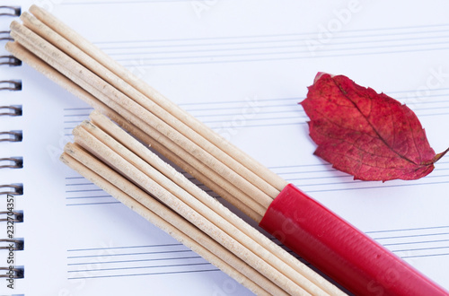 Hot rods for drummers on music sheets, bright red leaf