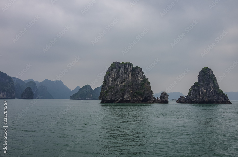 Beautiful limestone mountain scenery at Ha Long Bay, North Vietnam. Foggy weather in winter day. Beautiful limestone mountain scenery at Ha Long Bay, North Vietnam. Foggy weather in winter day.