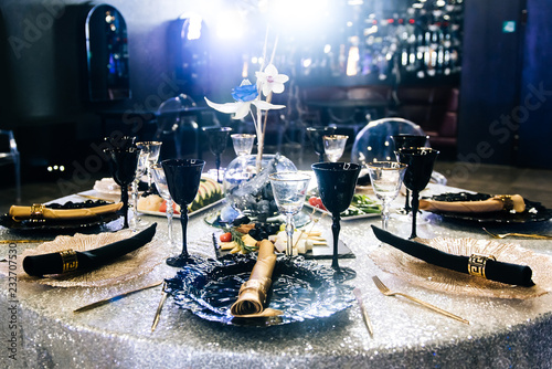 Tables set for an event party or wedding reception. luxury elegant table setting dinner in a restaurant. Black and gold glasses and dishes.