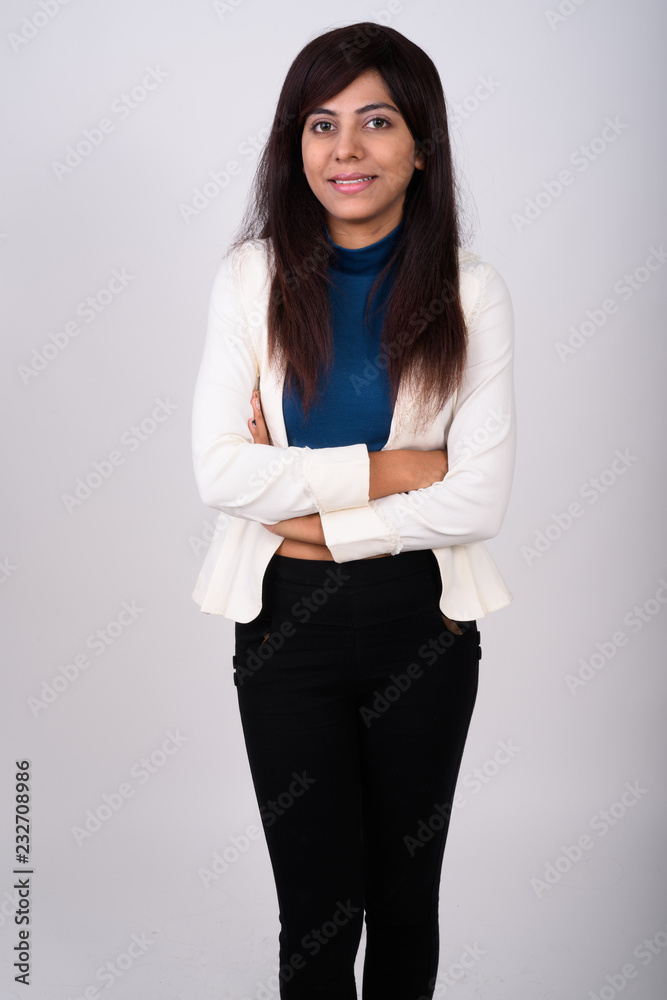 Studio shot of young happy Persian businesswoman smiling while s Studio shot of young happy Persian businesswoman smiling while s