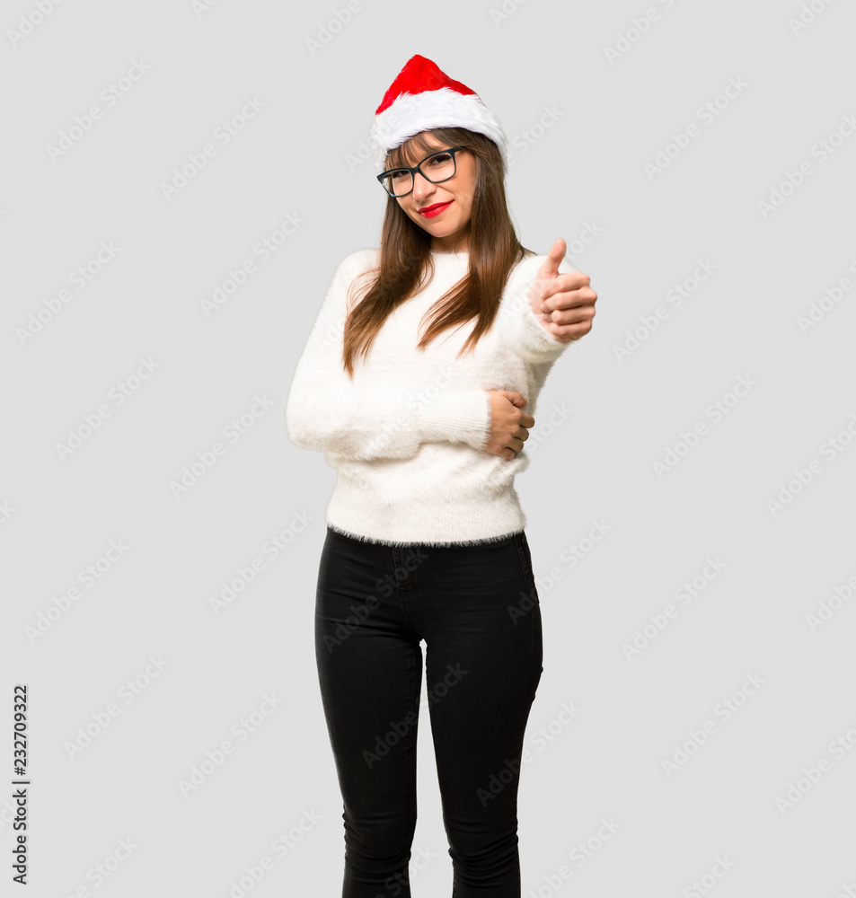Girl with celebrating the christmas holidays giving a thumbs up gesture and smiling on isolated grey background Girl with celebrating the christmas holidays giving a thumbs up gesture and smiling on isolated grey background