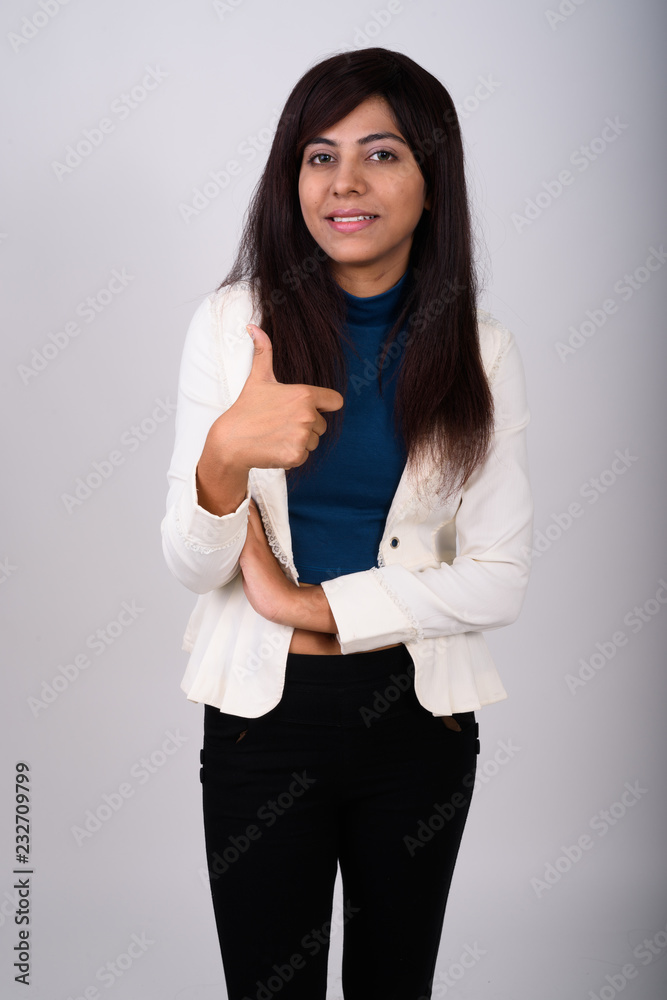 Studio shot of young happy Persian businesswoman smiling while g