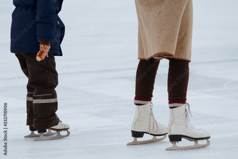 Mom teaches little son to ice skate. Unknowns boy with his mother ride on the ice rink Mom teaches little son to ice skate. Unknowns boy with his mother ride on the ice rink