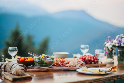 Salami platter and salad on a wooden table in the garden photo