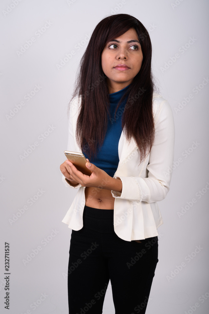 Studio shot of young Persian businesswoman thinking while holdin Studio shot of young Persian businesswoman thinking while holdin