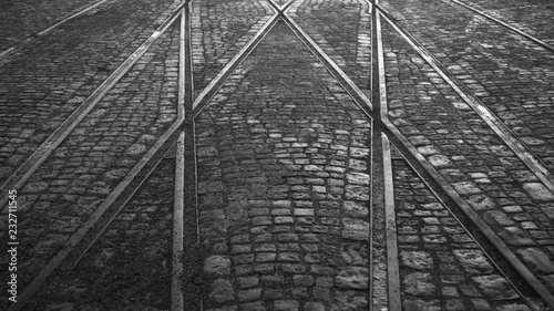 Fototapeta Naklejka Na Ścianę i Meble -  Crossing of tram rails on stone pavement in the city black and white background