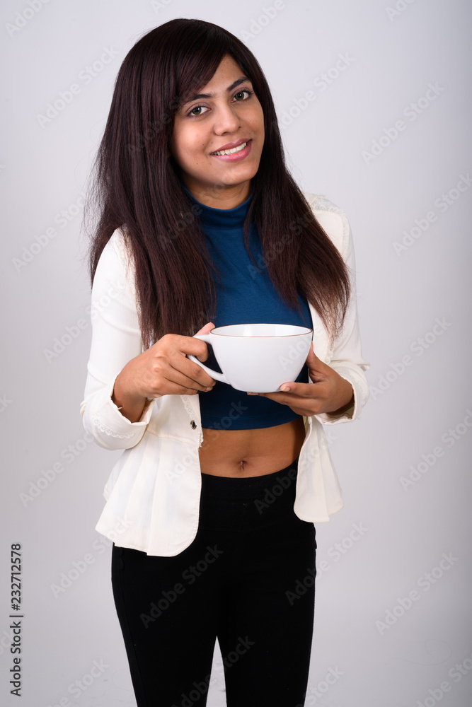 Studio shot of young happy Persian businesswoman smiling and sta Studio shot of young happy Persian businesswoman smiling and sta