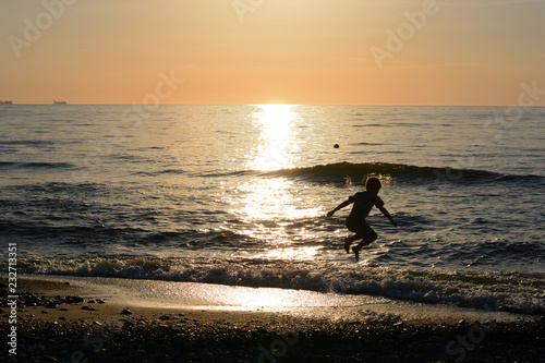 Fototapeta Naklejka Na Ścianę i Meble -  Boy jumping in the waves of the sea at sunset