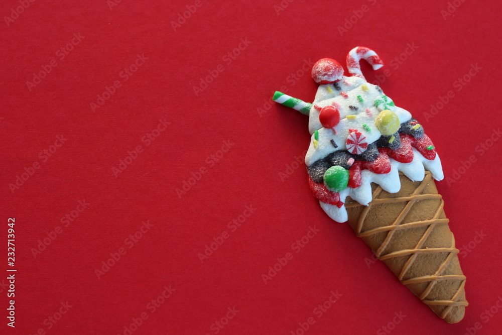 resin ice cream cone decorated with candy laying flat on a red background with writing space