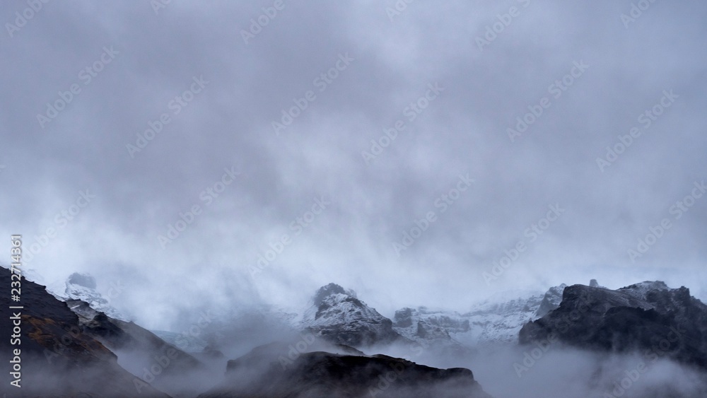 The snowy peaks of mountains revealed from behind the clouds on a winters day in Iceland The snowy peaks of mountains revealed from behind the clouds on a winters day in Iceland