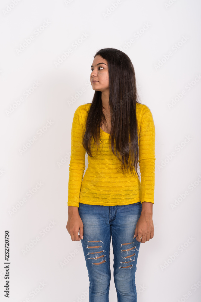 Profile view of young Indian woman standing while thinking with Profile view of young Indian woman standing while thinking with