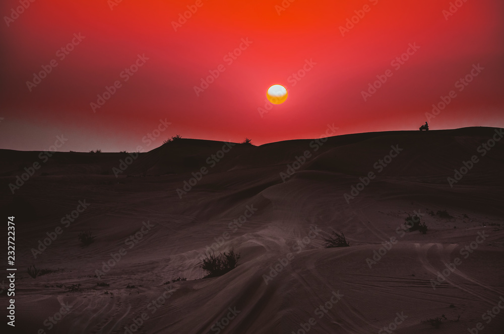 Motorrad auf einer Dühne in der Wüste bei Sonnenuntergang