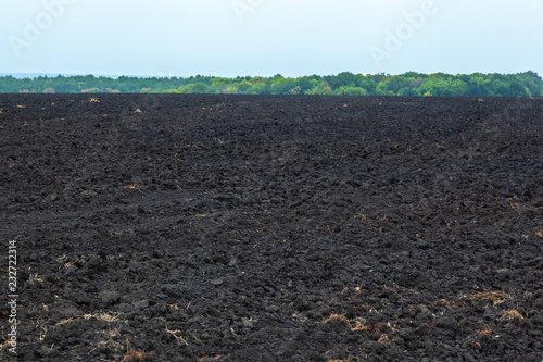 фотографія Black earth soil and rows of arable land on a plowed agricultural field