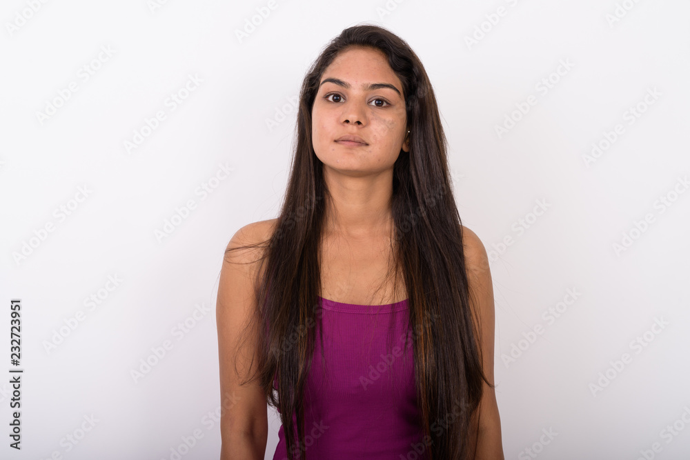 Studio shot of young Indian woman wearing sleeveless against whi Studio shot of young Indian woman wearing sleeveless against whi