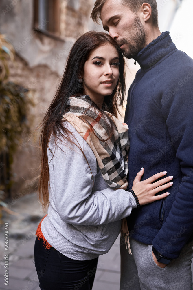Portrait of a young romantic couple hugging during the city walk at the warm autumn day. Two lovers are walking and hugging in Lviv, Ukraine Portrait of a young romantic couple hugging during the city walk at the warm autumn day. Two lovers are walking and hugging in Lviv, Ukraine