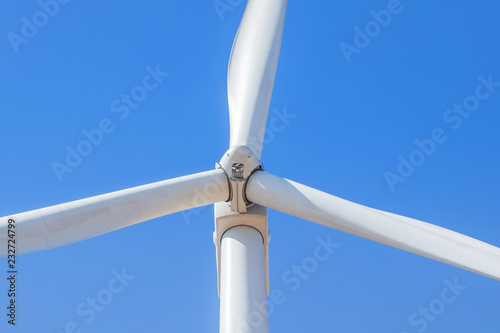 close up white wind turbine generating electricity producing in wind power station alternative energy with blue sky 