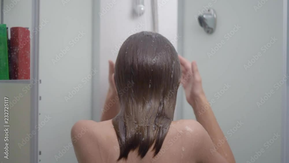 Young girl bathing under a shower at home - back view. Beautiful teen girl taking shower and washing in the bathroom. Happy child washing head, face and body with water. Stock Video | Adobe Stock