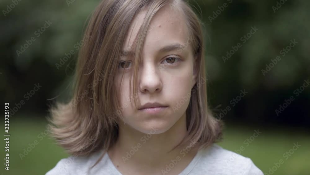 Close up emotional portrait of caucasian smiling teen girl. Funny cute teenager in summer park at day. Child looking at camera.