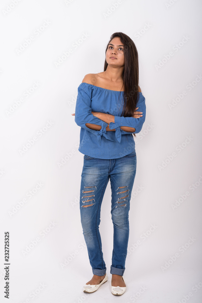 Full body shot of young Indian woman standing while thinking wit Full body shot of young Indian woman standing while thinking wit